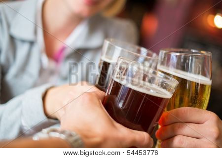People with beer toasting in a pub 