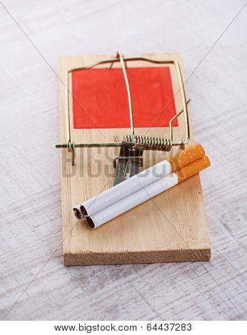 Mousetrap with cigarette, on wooden background