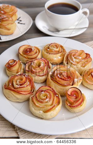 Tasty  puff pastry with apple shaped roses on plate on table close-up
