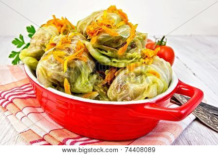 Cabbage stuffed and carrots in pan on board