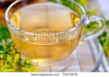 Tea from tutsan in glass cup on tablecloth