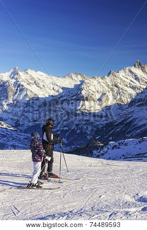 Men And Child On Ski At Winter Sport Resort In Swiss Alps