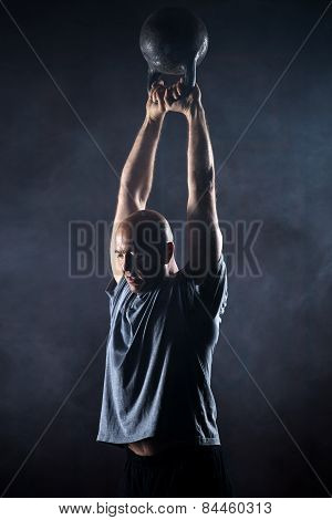 Bald charismatic athlete doing kettlebell swings.
