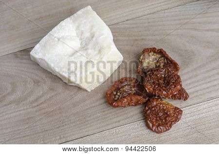 Parmesan and dried tomato on elm wood.
