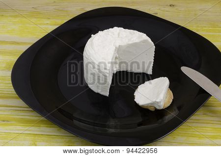 Fresh Cheese Knife Over Black Dish And Wood.