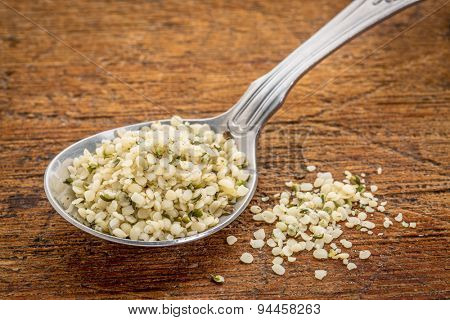 tablespoon of hemp seed hearts against rustic, scratches wood surface