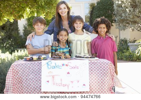 Group Of Children Holding Bake Sale With Mother