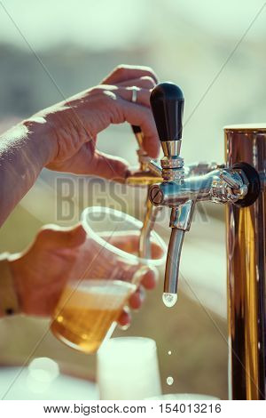 close-up of barman hand at beer tap pouring a draught lager beer