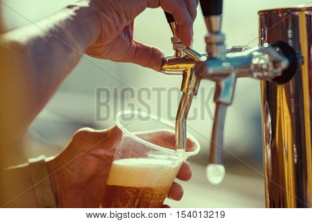 close-up of barman hand at beer tap pouring a draught lager beer
