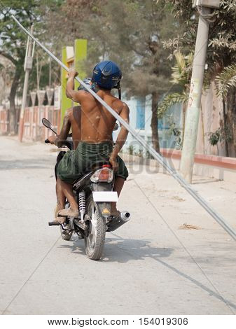 TWO WORKERS CARRYING METAL PIPES WITH MOTORCYCLE