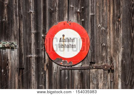 Prohibitory sign in german. Ausfahrt freihalten (keep exit clear). Old sign on a wooden door