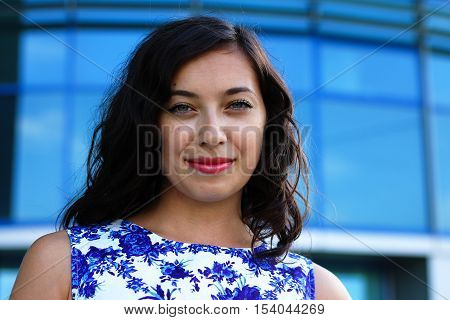 Beautiful smiling brunnete lady in white-blue dress outdoors