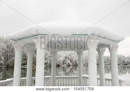 beautiful gazebo with columns on a background of the winter lake and the park