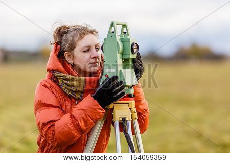 Girl Surveyor works with total station on the field.