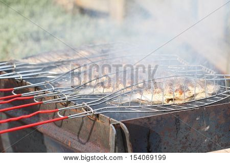 Fish grill / There are fish on the grill and grilled. An raw freshwater fish on the grill. Cooked in traditional style. Cooking of salted fish on a grill stove.