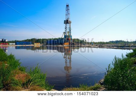 Drilling rig with reflection in the water. Siberia.