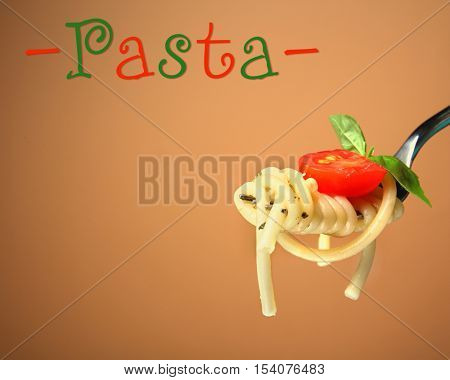 Fork with delicious pasta, tomato and basil on color background. Italian food concept. Word PASTA on color background.