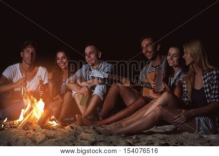 Happy friends near fireplace on the beach
