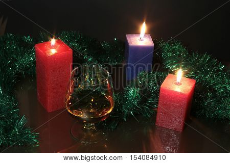 christmas photo cognac glass and candle on black background.