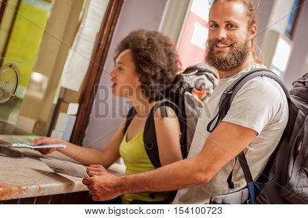 Happy Couple Of Tourists Buy Tickets At Terminal Station Counter