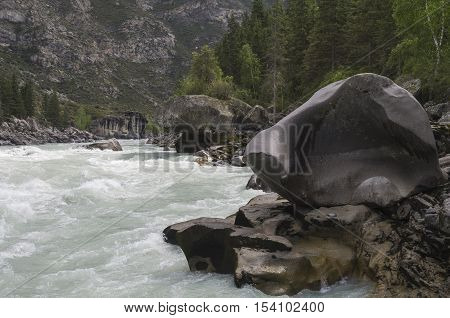 Bizarre stone on the shore of a mountain river. Rapids 