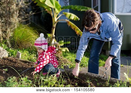 Mother And Child Works In The Garden