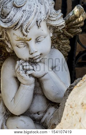 Vertical photo in color of a stoned Cherub from a graveyard