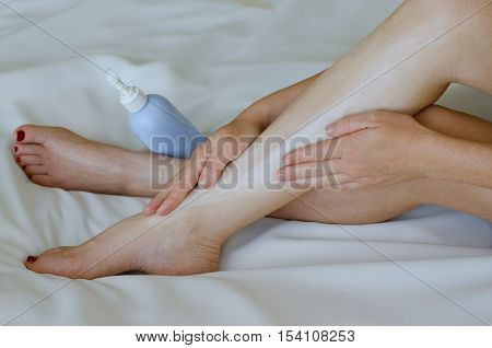 Young Woman Moisturisers Her Legs On White Background