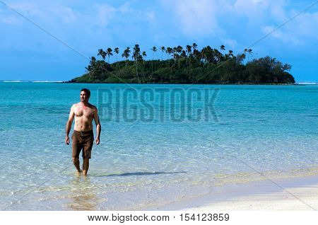 Young happy man on vacation comes out of the water on Muri beach lagoon in Rarotonga Cook Islands. Photo by Rafael Ben-Ari/Chameleons Eye