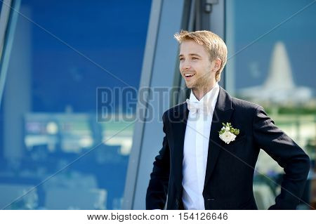Handsome groom's portrait outdoors on summer day