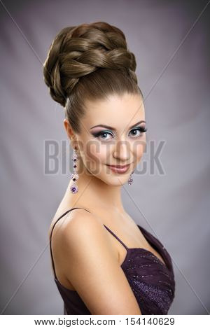 Beautiful girl with bright makeup and high hair.On gray background.