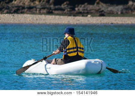 Man rows a rubber inflatable dinghy boat.