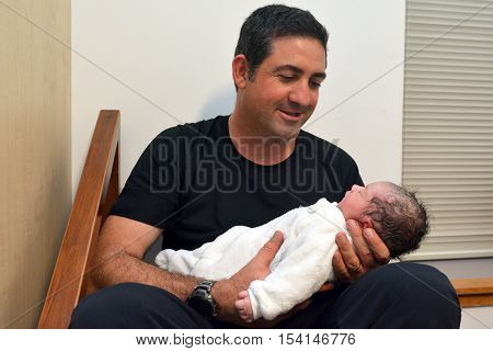 Happy father holds his newborn baby few minutes after childbirth.