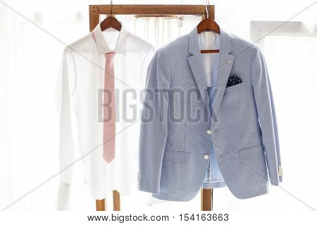 White shirt with necktie and gray suit of groom hanging on hanger wedding clothing