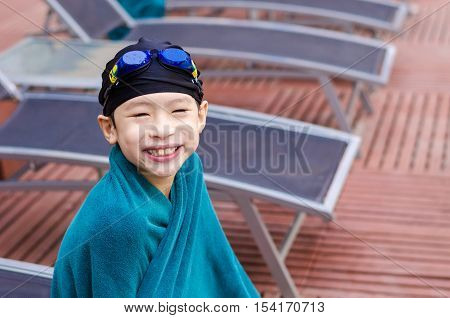 Young asian boy sitting beside the pool after swimming