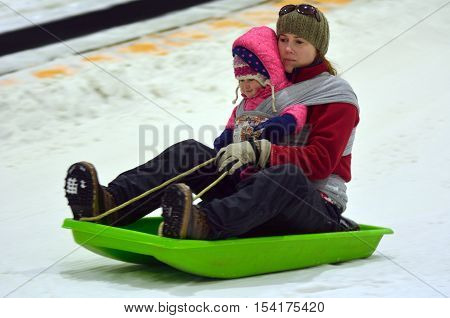 Mother With Child On A Snow Slid Slide Downhill