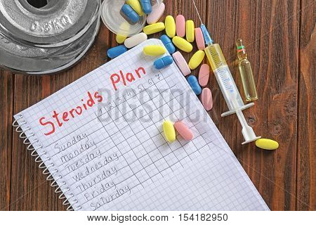 Notebook and drugs on wooden background