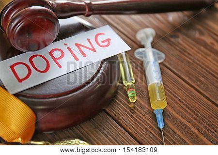 Gavel, word Doping and syringe on wooden background