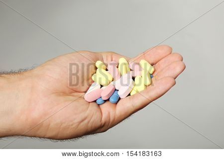 Male hand holding drugs on color background