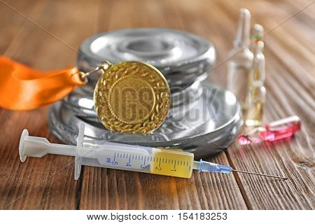 Syringe, medal and weight disks on wooden background