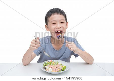Young asian boy eating vegetables salad over white