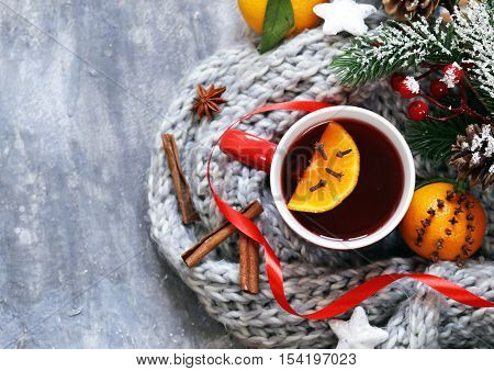 Traditional winter beverage mulled wine. Christmas drink. Gray background with knitted scarf