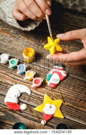 Girl in a bright sweater paints porcelain figurines.