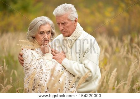 Portrait of a sad elderly couple standing embracing outdoors