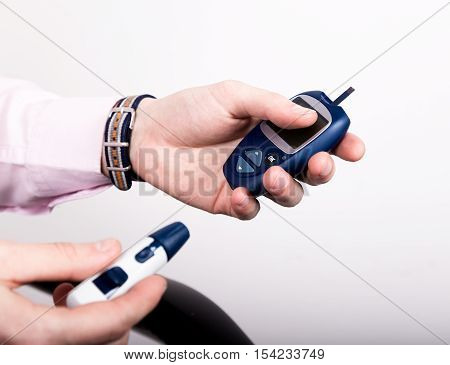 Dependent first type diabetes patient. Measuring glucose level blood test using ultra mini glucometer and small drop of blood from finger and test strips.