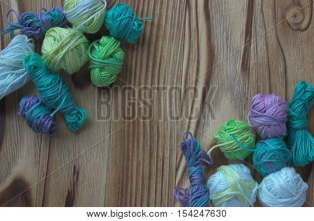 Many small multicolor melange cotton yarn balls for knitting crochet on wooden rustic background backdrop