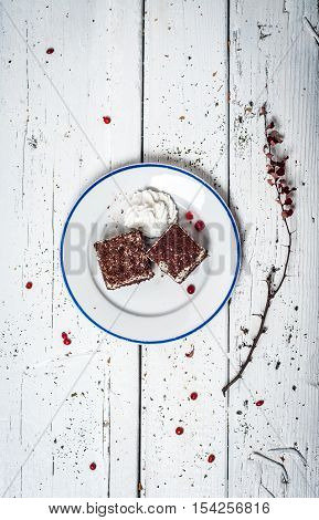 Chocolate cake with cream and fruit on retro wooden table