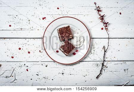 Chocolate cake with cream and fruit on retro wooden table