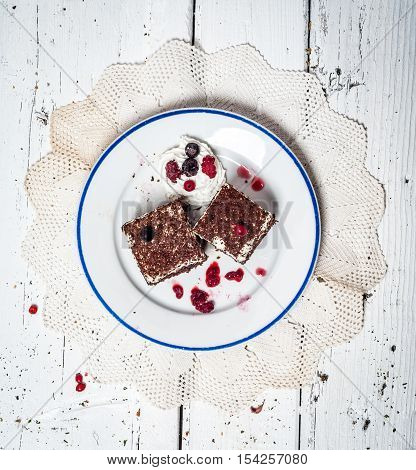 Chocolate cake with cream and fruit on retro wooden table