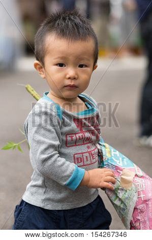 Takayama Japan - September 24 2016: Closeup of young Japanese boy carrying a bouquet of flowers on the public morning market in front of the Jinya Hall. Combination of colors.